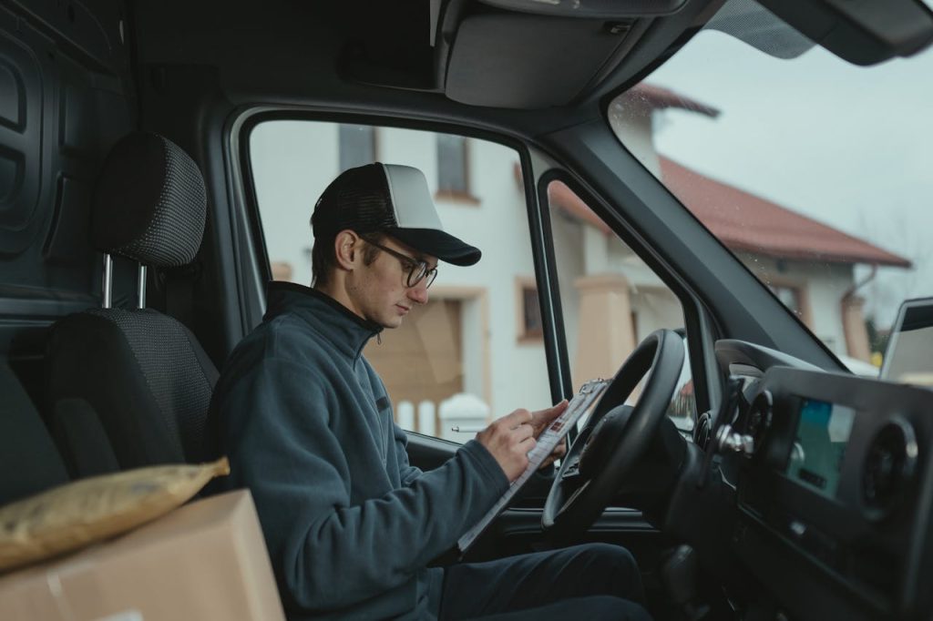 A courier inside a delivery van preparing packages for delivery, showcasing logistics work.